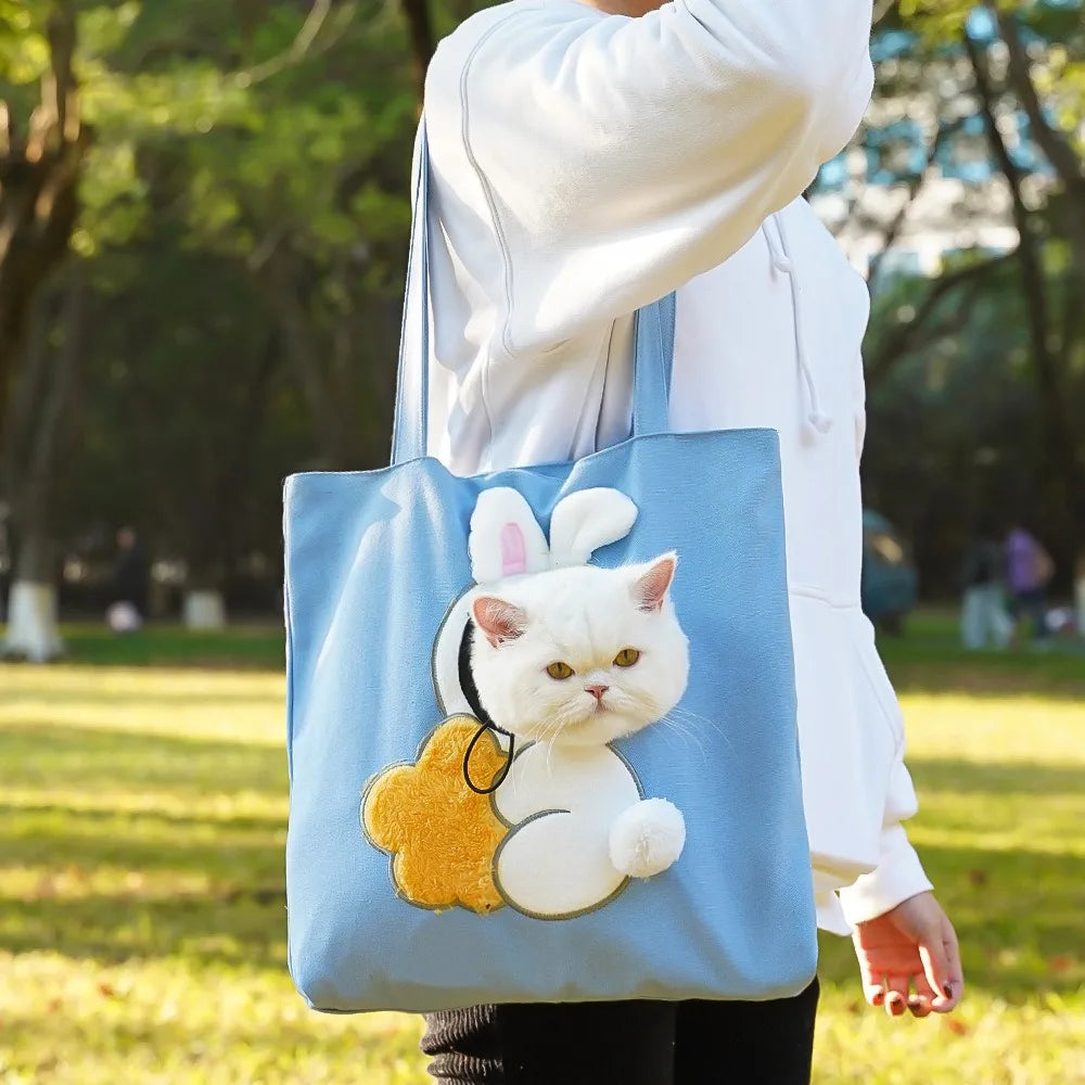 Blue PeekaBag with a cat riding head-out in a park